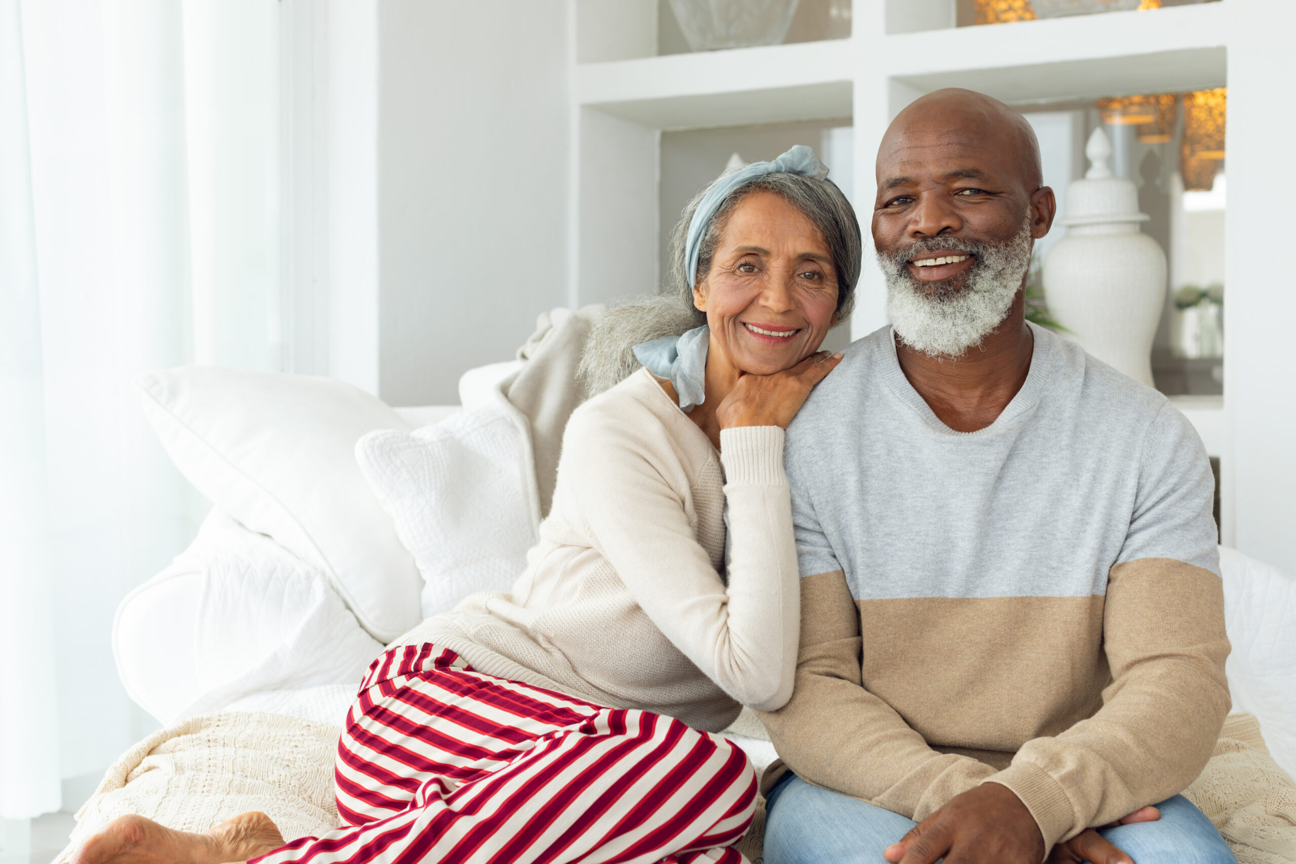Senior African American couple sitting on the couch in their home smiling